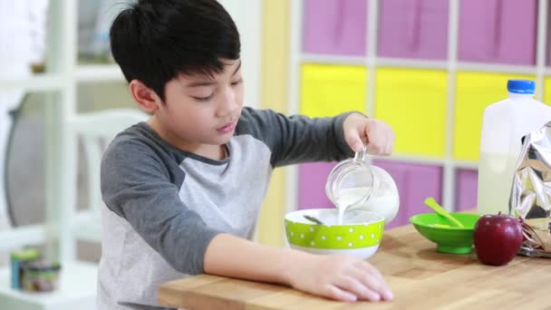 Kleine Aziatische jongen eten granen met melk met glimlach gezicht — Stockvideo