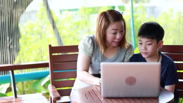 Young, happy mother with child using laptop on terrace — Stock Video