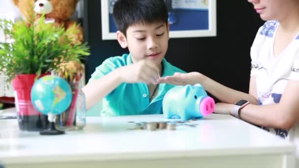 Asiatiska mamma att hjälpa sonen att spara pengar i spargrisen — Stockvideo