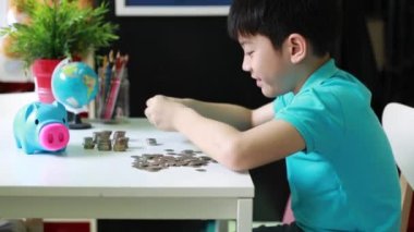 Mutlu Asyalı çocuk paraları kumbara ve yerine birlikte sayma