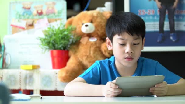 4k, Jovem asiático menino navegando na internet em um tablet digital em casa . — Vídeo de Stock