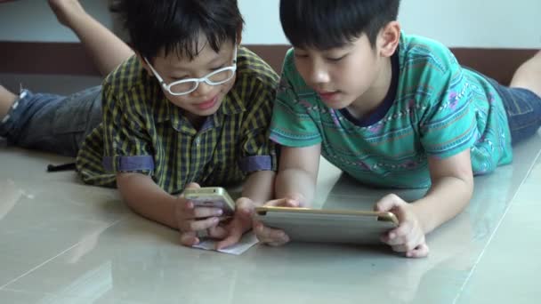4K, щасливий Азіатський хлопчик граючи онлайн ігри на планшетному комп'ютері та смартфоні . — стокове відео