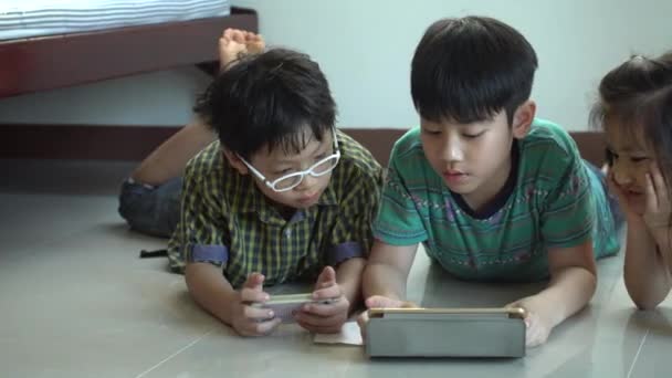 4K, Joven niño asiático jugando juegos en línea en la computadora tableta y el teléfono inteligente  . — Vídeo de stock