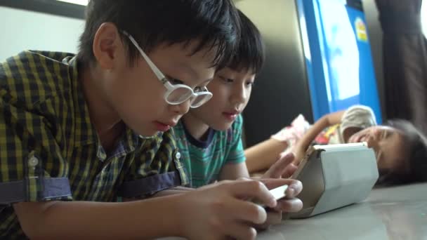 4k,タブレットコンピュータとスマートフォンでオンラインゲームをプレイするアジアの若い子供 . — ストック動画