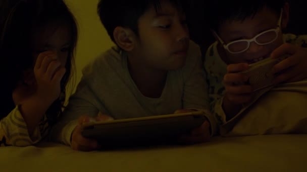 Молодой азиатский ребенок играет в игры на мобильном телефоне, свет от игры отражаются на их лице  . — стоковое видео