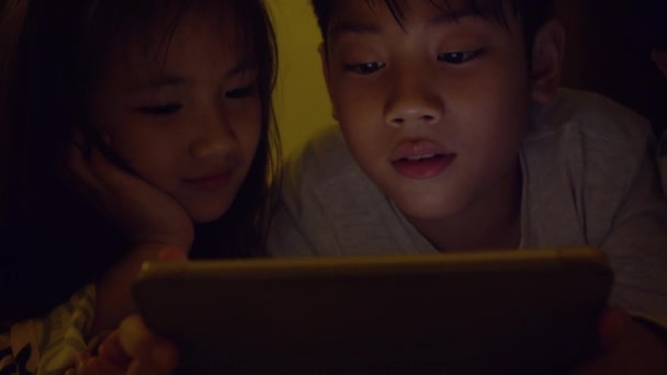 Unga asiatiska barn spelar spel på mobiltelefon, Ljuset från spelet reflektera över deras ansikte . — Stockvideo
