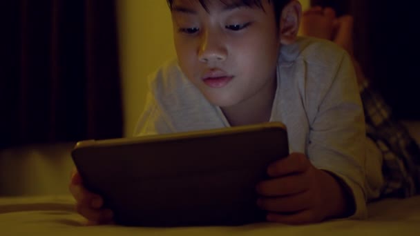Young asian child playing game on mobile phone, The light from the game reflect on their face . — Stock Video