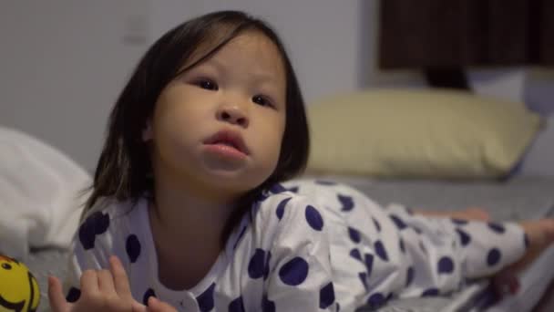 Pequeña chica asiática viendo la televisión en la cama — Vídeos de Stock