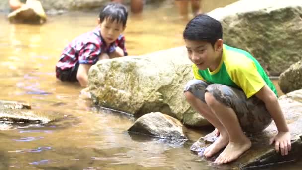 4k, two asiatisch süß junge sit und spielen im die fluss . — Stockvideo