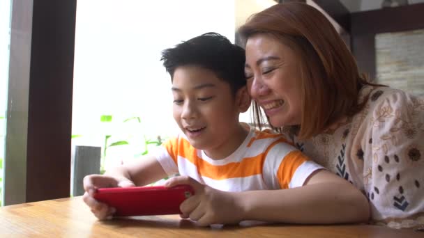 4K, Счастливый азиатский мальчик и его мама играют в игры на смартфоне — стоковое видео