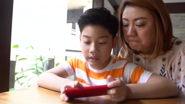 4k, ευτυχισμένος Ασίας αγόρι και τη μαμά του να παίζετε παιχνίδια στο έξυπνο τηλέφωνο — Αρχείο Βίντεο