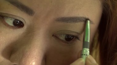 Makyaj uygulamak ve aynaya bakarak Asyalı kadın 