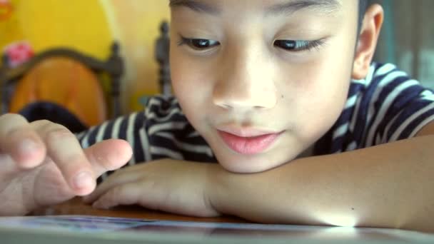 Счастливый азиатский ребенок смотрит и играет на планшетном компьютере — стоковое видео