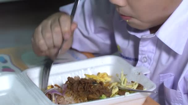 Asiática niño en estudiante uniforme comer alimentos en plástico espuma caja — Vídeos de Stock