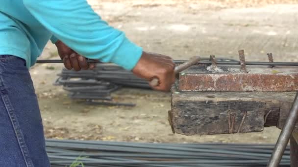 Trabajador doblar la línea de acero en forma cuadrada. Al edificio de construcción, un poste que soporta una pila de vigas — Vídeo de stock