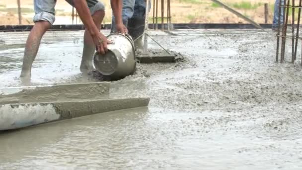 Неидентифицированные строители наливают бетонную смесь из бетоносмесителя . — стоковое видео