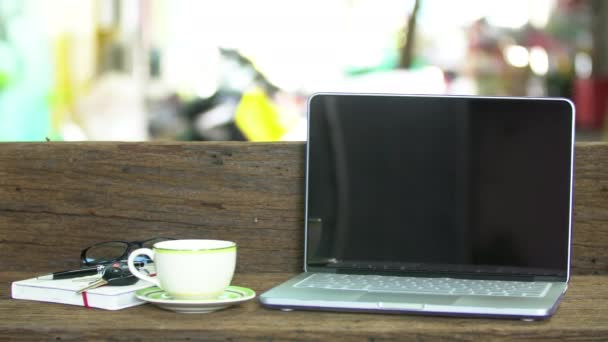 Mesa de madeira com um laptop, local de trabalho ao ar livre sob árvore grande . — Vídeo de Stock