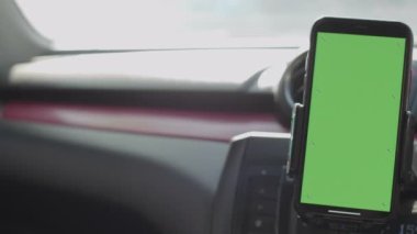 Phone on Car Dashboard Green Screen, Smartphone with a green screen is fixed on the dashboard.