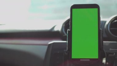 Phone on Car Dashboard Green Screen, Smartphone with a green screen is fixed on the dashboard.