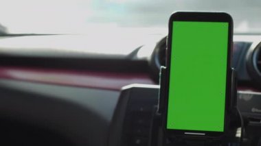 Phone on Car Dashboard Green Screen, Smartphone with a green screen is fixed on the dashboard.