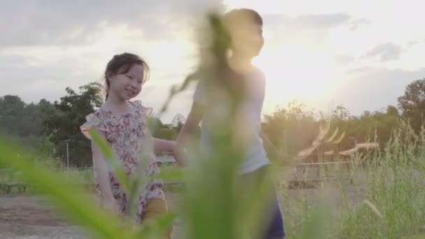 アジアの兄弟姉妹が楽しそうに走り遊ぶ自然の中で太陽が沈む夜 — ストック動画