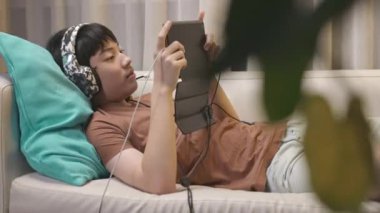 Genç çocuk çevrimiçi oyunlara bağımlıydı, uzanıp evdeki uzun bir kanepede tablet bilgisayar oynuyordu. Dolly vur.