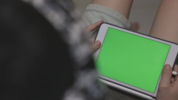 緑の画面フレームとタブレットパッドタッチスクリーン技術を使用して保持匿名の手 リビングルームのインテリアに座ってポータブルデバイス上でオンライン読書を閲覧 肩のビュー ドリー撮影 — ストック動画