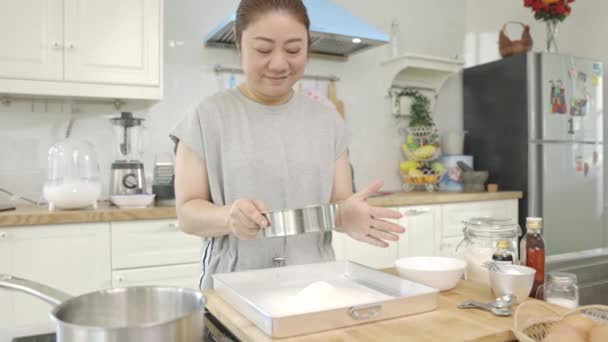 아시아의 여자들은 밀가루를 시추하여 과자를 만들고 천천히 얼굴로 집에서 케이크를 — 비디오