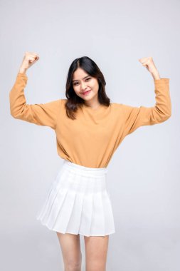 Genç Asyalı kadın portreleri. İki elini de kaldır. Gülümseyen bir yüzle, kendine güveni olan güzel bir kadın, beyaz bir arka planda güzel ve mutlu görünüyor..