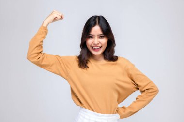 Genç Asyalı kadın portreleri. Kollarını kaldır. Gülümseyen bir yüzle, kendine güveni olan güzel bir kadın, gri arka planda güzel ve mutlu görünüyor..