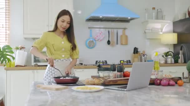 Piękna Azjatka Robi Śniadanie Patrząc Jak Zrobić Komputerem Laptopa Szczęśliwej — Wideo stockowe