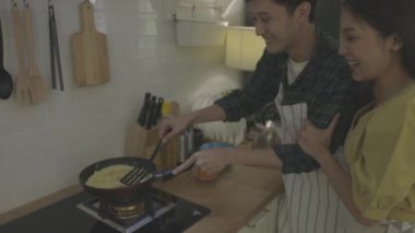 Genç evli çift evde romantik bir ortamda yemek pişirmeye yardım ediyor. Çiftler aşklarını kahvaltıda birbirlerine yardım ederek gösterirler..