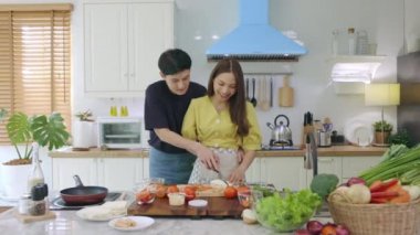 Yeni evli bir çift, mutlu bir şekilde yemek pişirmek ve evde eğlenmek için birbirlerine yardım ederler. Çiftler birlikte güzel, mutlu yemekler yaparak vakit geçirirler..