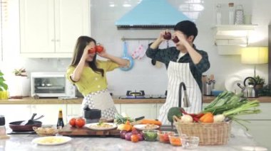 Asyalı çift, evdeki mutfakta romantik bir ortam yaratmak için birbirlerine yardım ediyorlar. Gençler karıştırmadan önce ahşap bir kasede malzemeleri karıştırmak için birlikte çalışırlar..