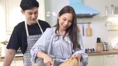 Asyalı çift, evdeki mutfakta romantik bir ortam yaratmak için birbirlerine yardım ediyorlar. Genç kadınlar güler yüzlü ve mutlu yüzlü bayramlarda yemek pişirmeye yardım eder..