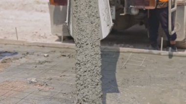 Karıştırıcı çimento kamyonundan akan ve dökülen beton inşaat alanındaki iş yoluna sıvı beton döküyor..
