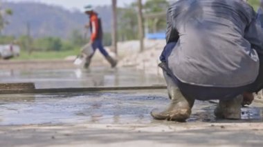Beton yolun yüzeyini pürüzsüz ve güzel olması için ayarlayan işçinin arka görüntüsü. Beton yollar yapan isimsiz bir zanaatkar..