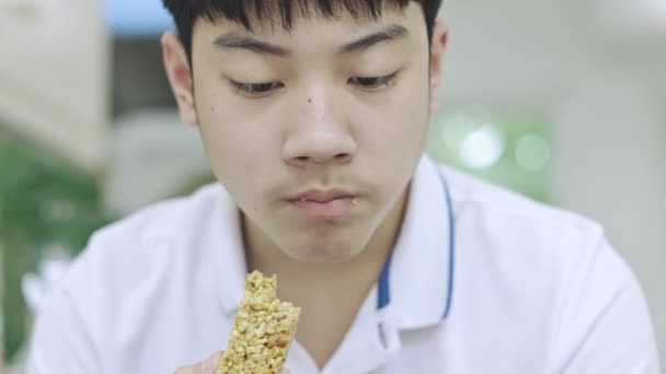 Ásia Teen Menino Comer Lanches Enquanto Usando Telefone Mesmo Tempo — Vídeo de Stock