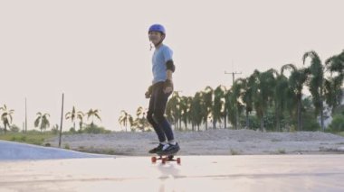 Mutlu Asyalı genç çocuk, Virüs salgını anında evinde park yerinde spor yaşam tarzıyla spor yaparak sörf yapıyor. Yavaş çekim .