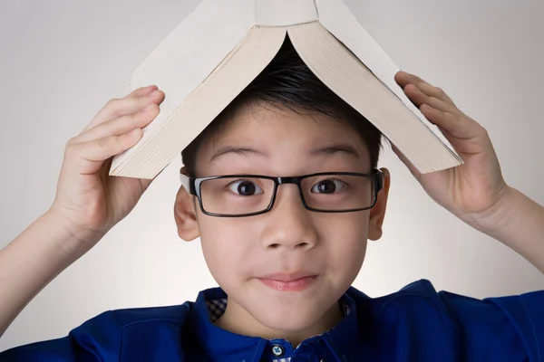 Asiatiska pojke med boken på huvudet tänkande — Stockfoto