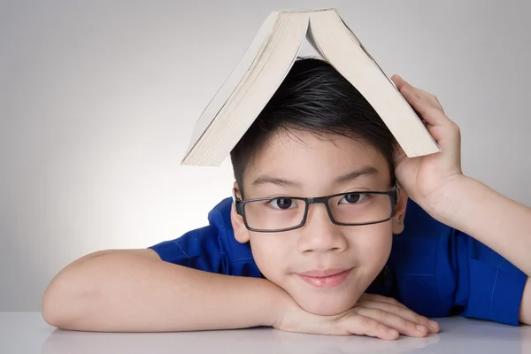 Asiático chico con libro en cabeza pensamiento — Foto de Stock