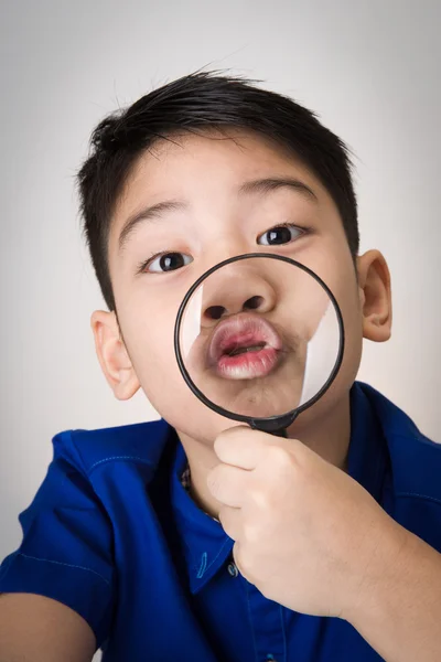 Portrait d'un jeune enfant asiatique regardant à travers une gla grossissante — Photo