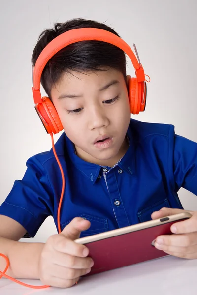 Asiático chico ware auriculares y jugando el teléfono celular — Foto de Stock