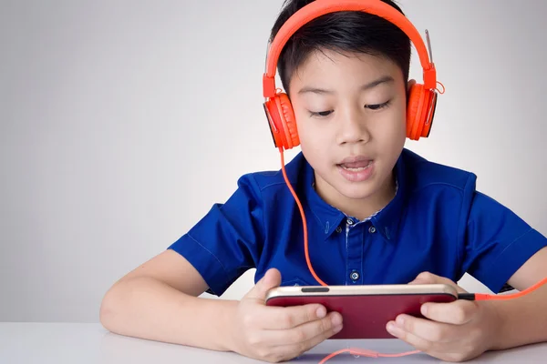 Asijské boy konzumní sluchátka a hraje na mobilní telefon — Stock fotografie