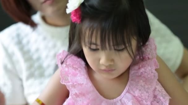 Азіатський дівчинка з матір'ю виконання домашніх завдань на стіл — стокове відео