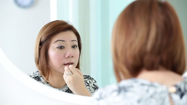 Femme asiatique appliquant le maquillage et regardant miroir dans la chambre . — Video