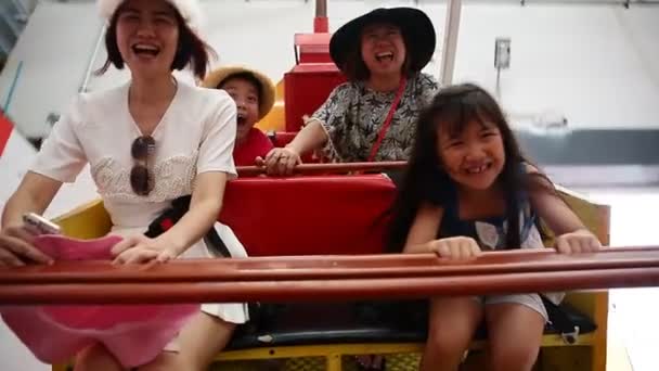 Happy Asian child with mother playing speed boat in amusement park — Stock Video