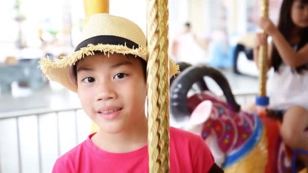 Lose up of asian child riding carousel at carnival — Stock Video