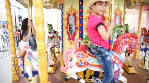 Lose up of asian child riding carousel at carnival — Stock Video