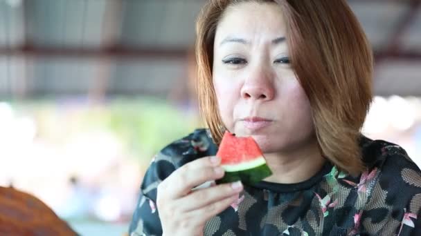 Šťastná Asijská samice se baví jíst zralý meloun .